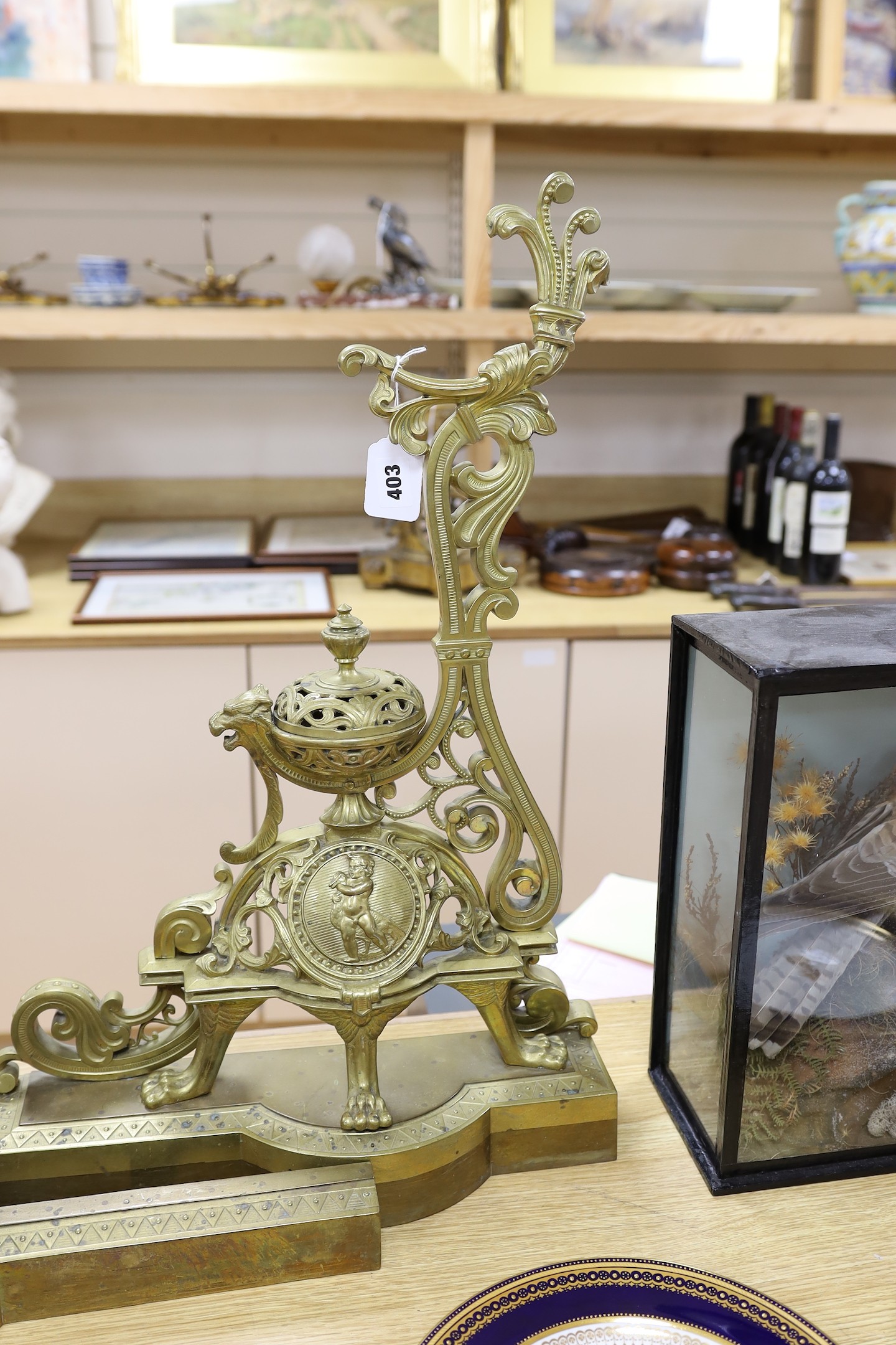 A pair of French bronze chenets, 19th century, with ornate decoration and cherub cartouche, adjustable curb, 64 cms high